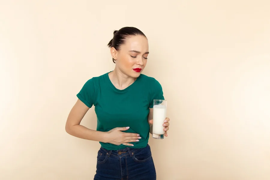 front-view-young-female-dark-green-shirt-blue-jeans-holding-milk-having-stomachache-beige